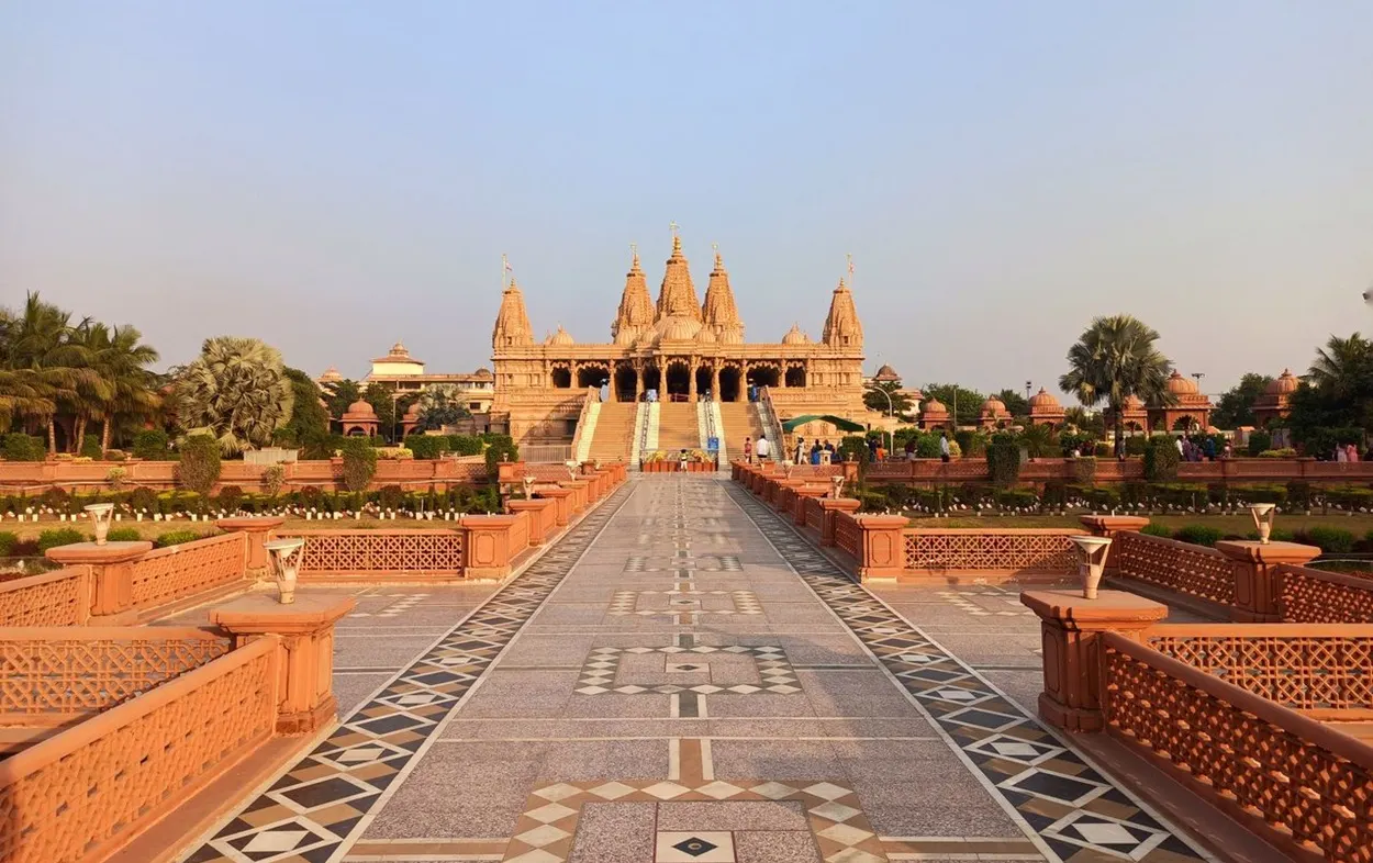 Intricately carved pink sandstone temple facade and green lawns of Swaminarayan Akshardham Delhi