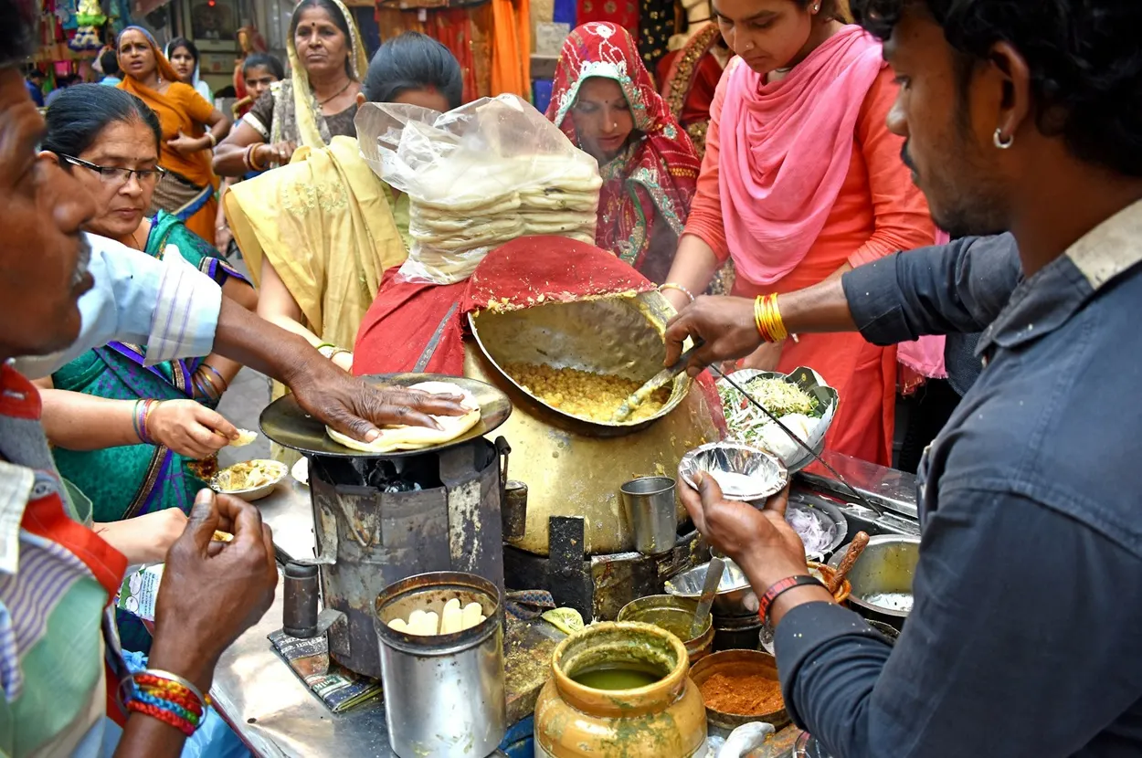 Street food vendor serving hot matar kulcha to crowds in Chandni Chowk Old Delhi