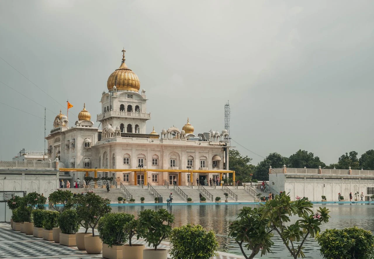 White marble structure and golden dome of Gurudwara Bangla Sahib reflected in the holy pond water