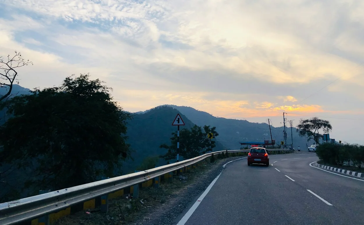 Car driving on a winding scenic mountain road towards Kasauli hill station