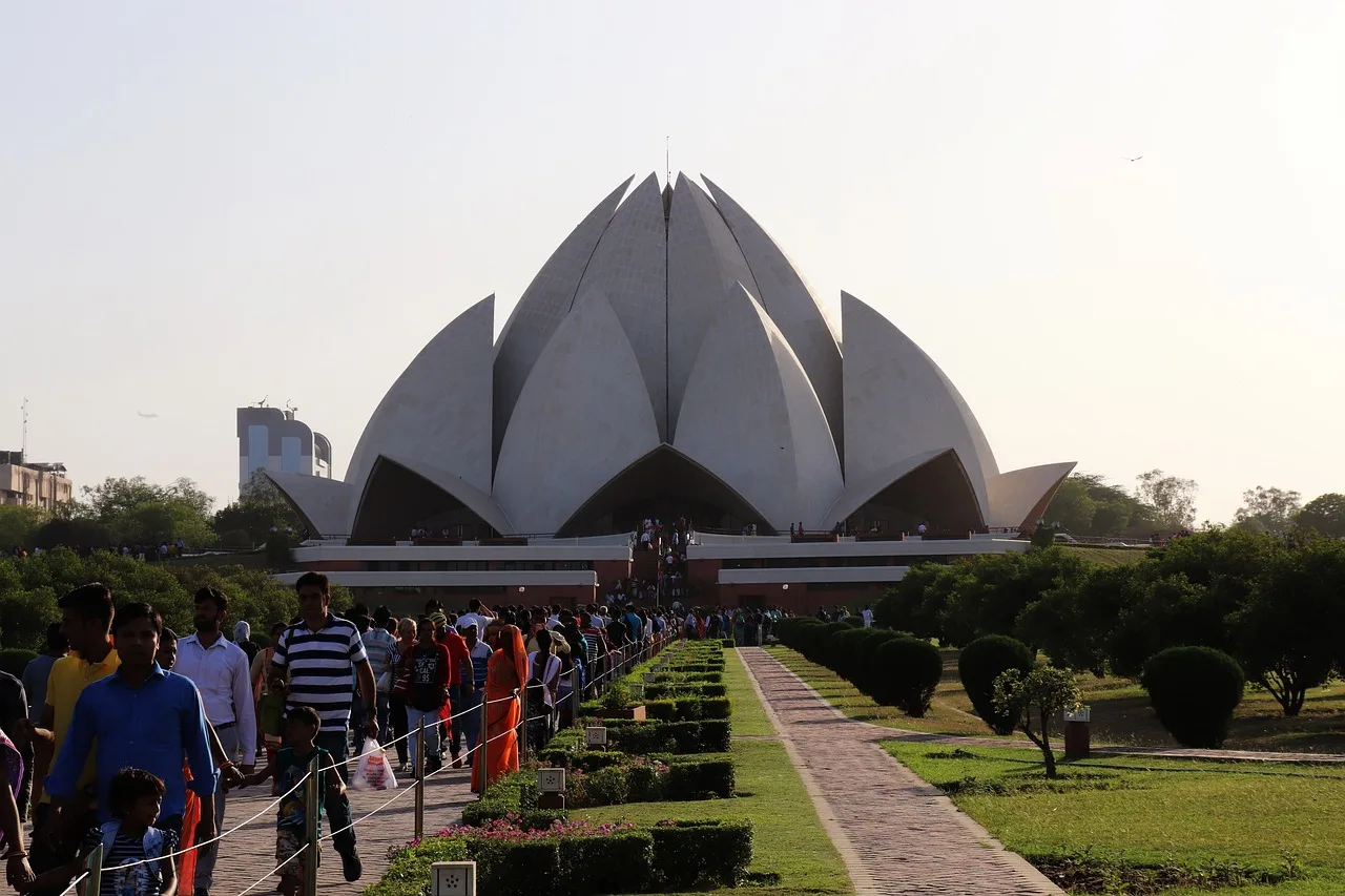 White lotus flower shaped marble architectural structure surrounded by blue pools at Lotus Temple