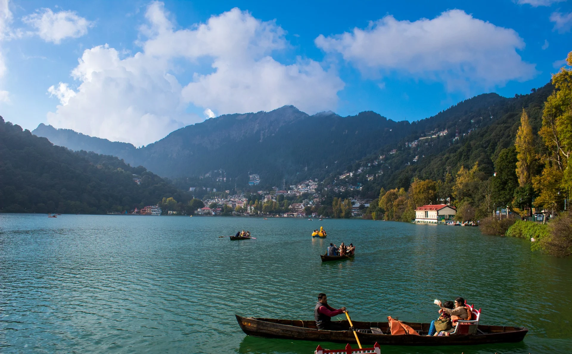 Colorful boats floating on Naini Lake surrounded by hills in Nainital