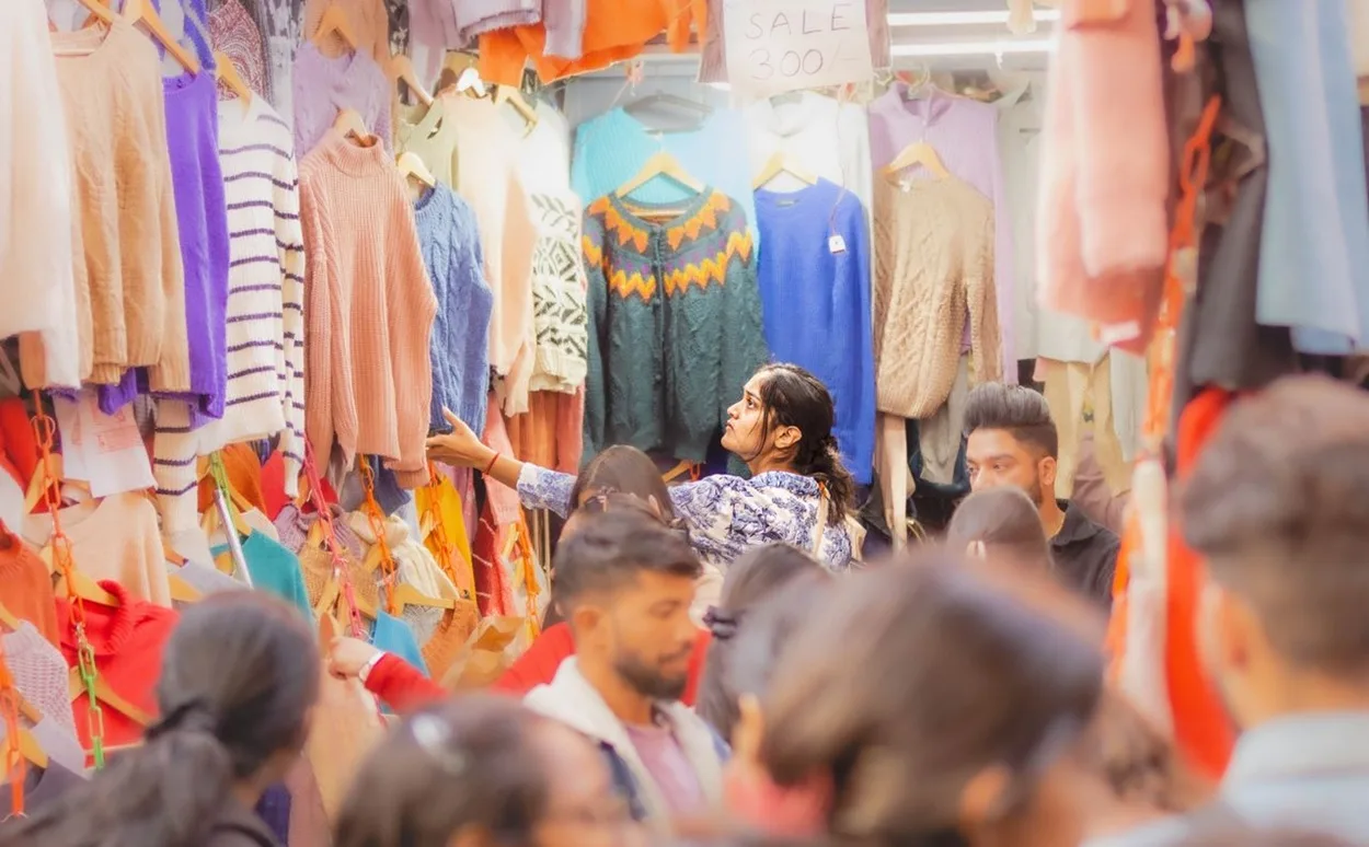 Crowded street market stall with clothes hanging on racks and SALE price signs in Sarojini Nagar Delhi