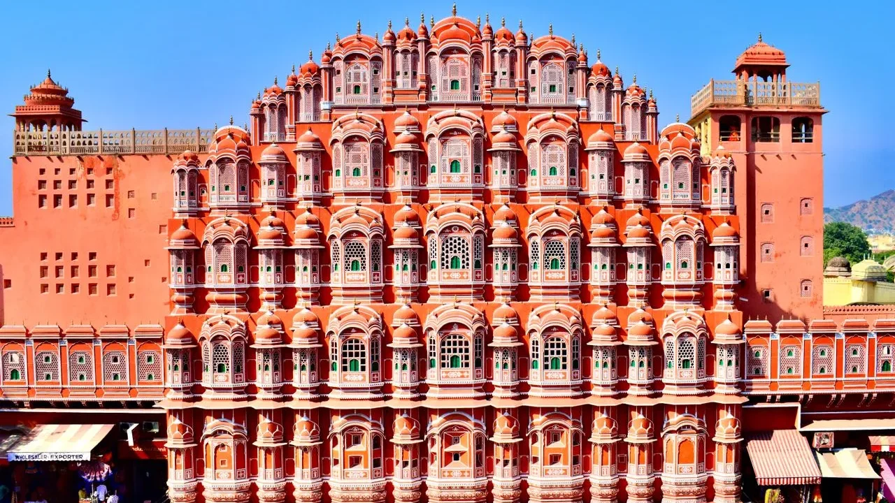 Pink and red sandstone honeycomb facade of Hawa Mahal with intricate jharokha windows in Jaipur, Rajasthan