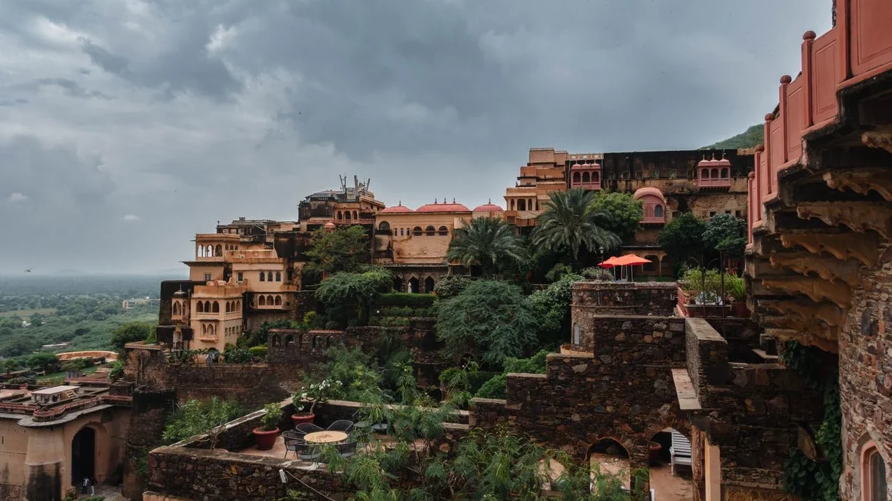Tiered sandstone courtyards and ramparts of Neemrana Fort-Palace illuminated during sunset along the Delhi-Jaipur highway