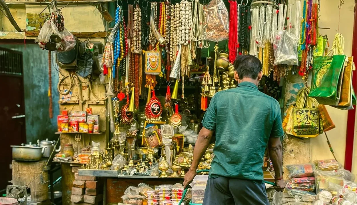Local artisan shopkeeper displaying traditional jewelry and handicrafts in an Agra market bazaar