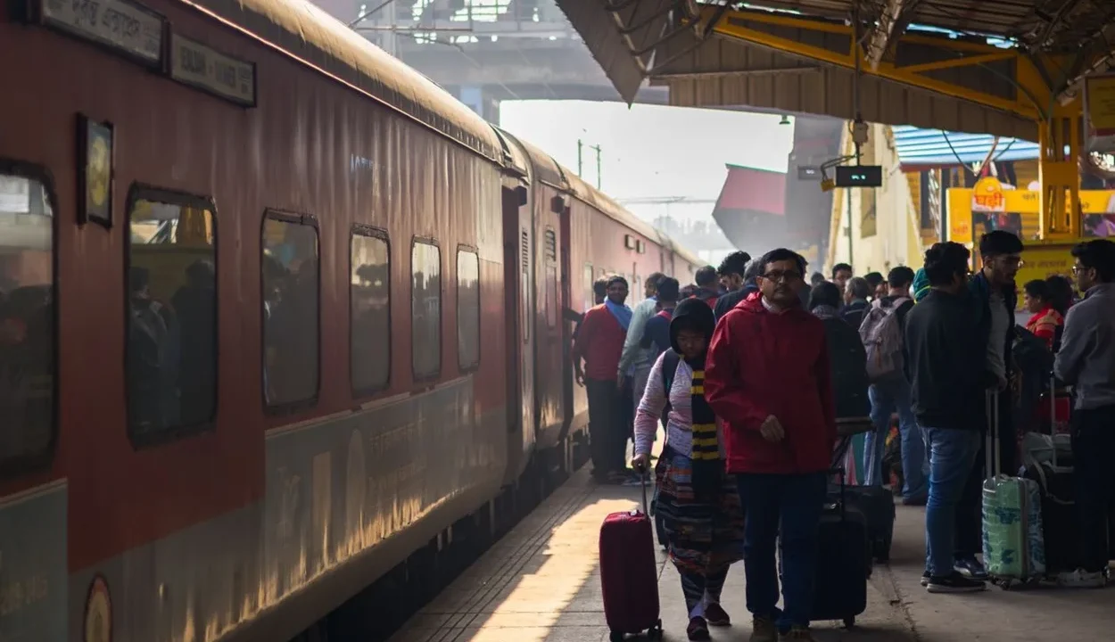 Passengers with luggage walking on a railway station platform next to an express train in India