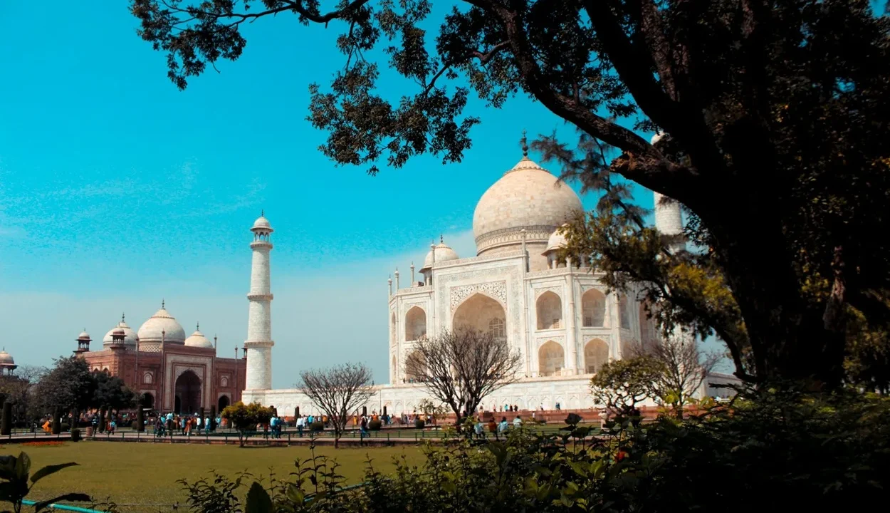 Majestic white marble Taj Mahal reflecting in the garden pool under clear blue sky in Agra