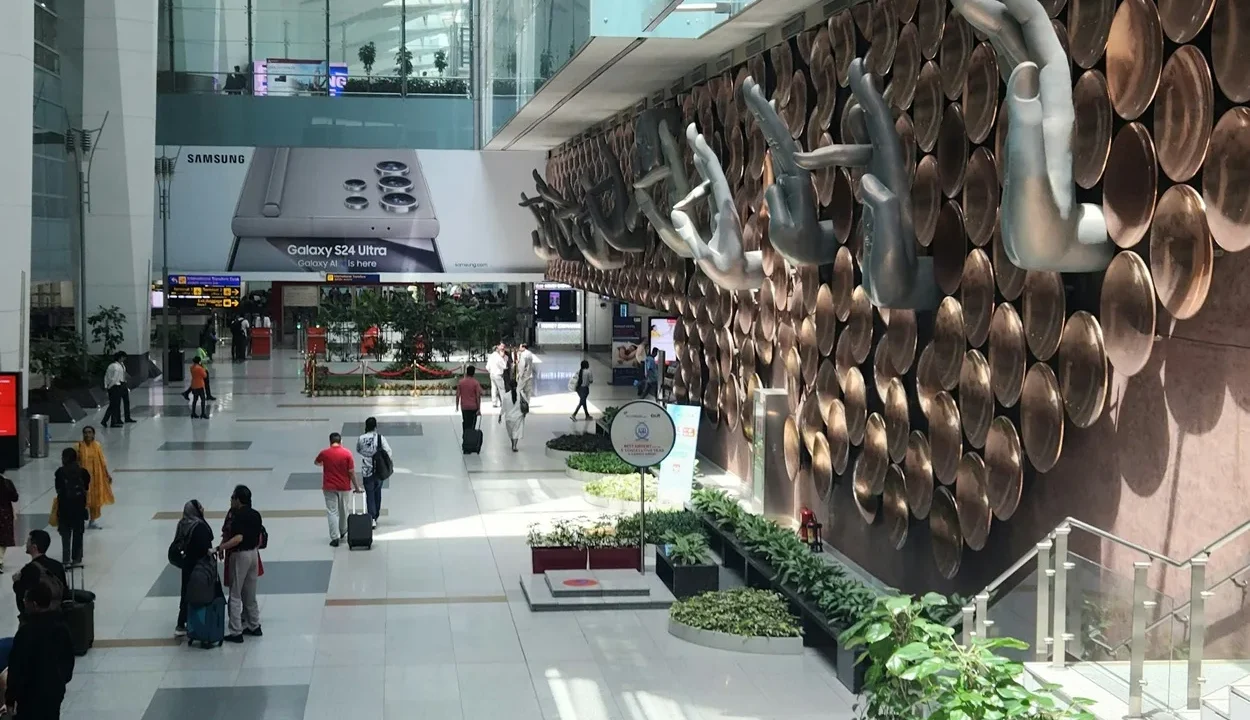 Passengers with luggage entering the orange-branded Delhi Metro Airport Station outside Terminal 3 at Indira Gandhi International Airport