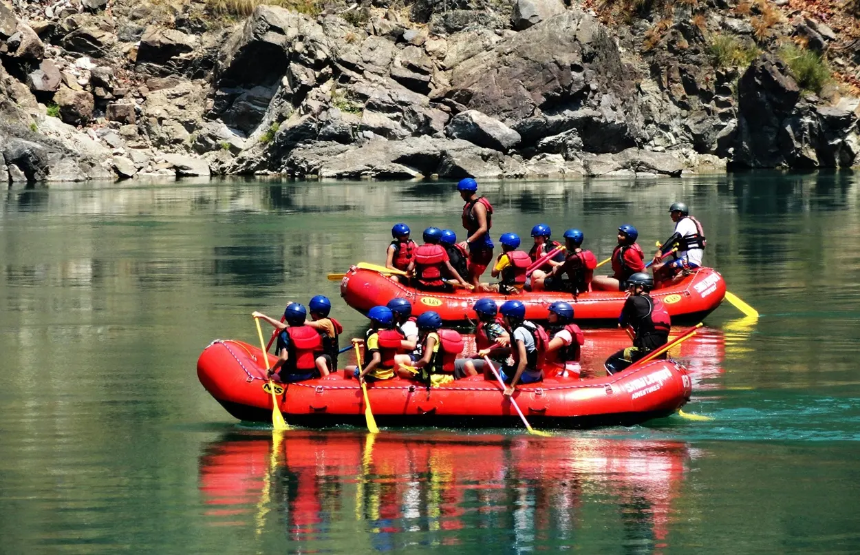 Rafting group with safety gear paddling on the calm stretches of the Ganges River in Rishikesh