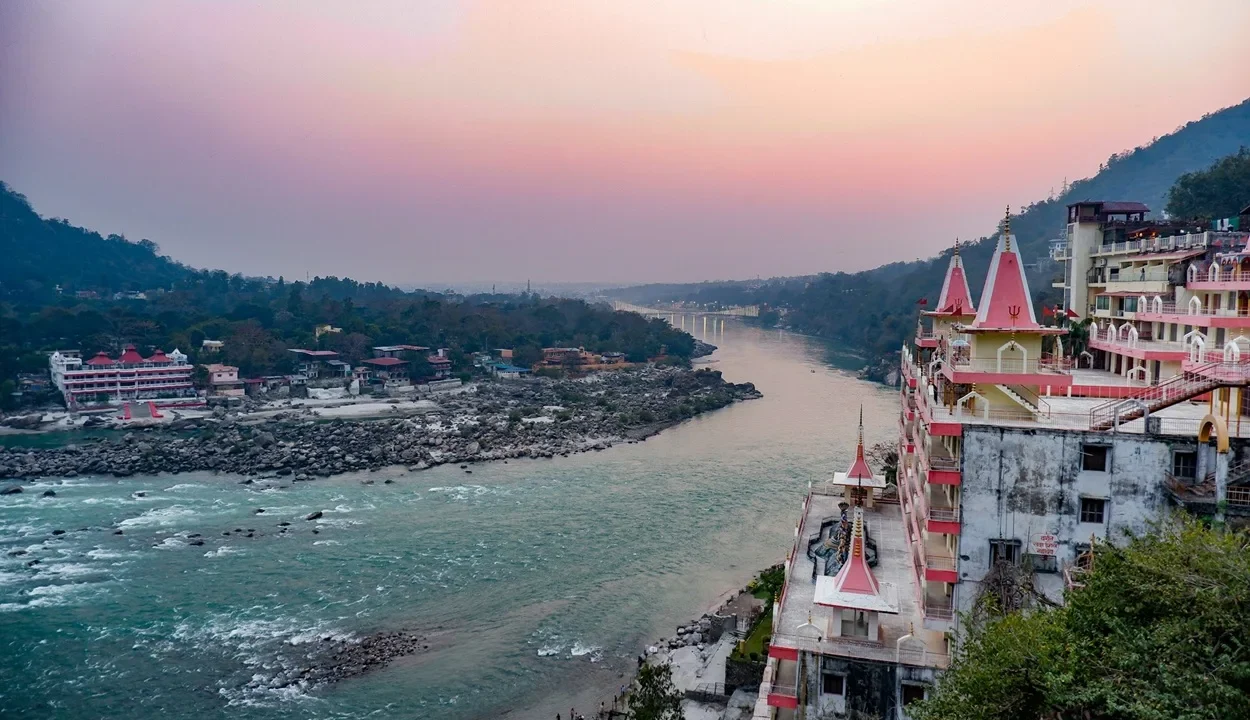 Elevated view of riverfront ashrams and hotels along the Ganges near Tera Manzil Temple in Rishikesh at sunset