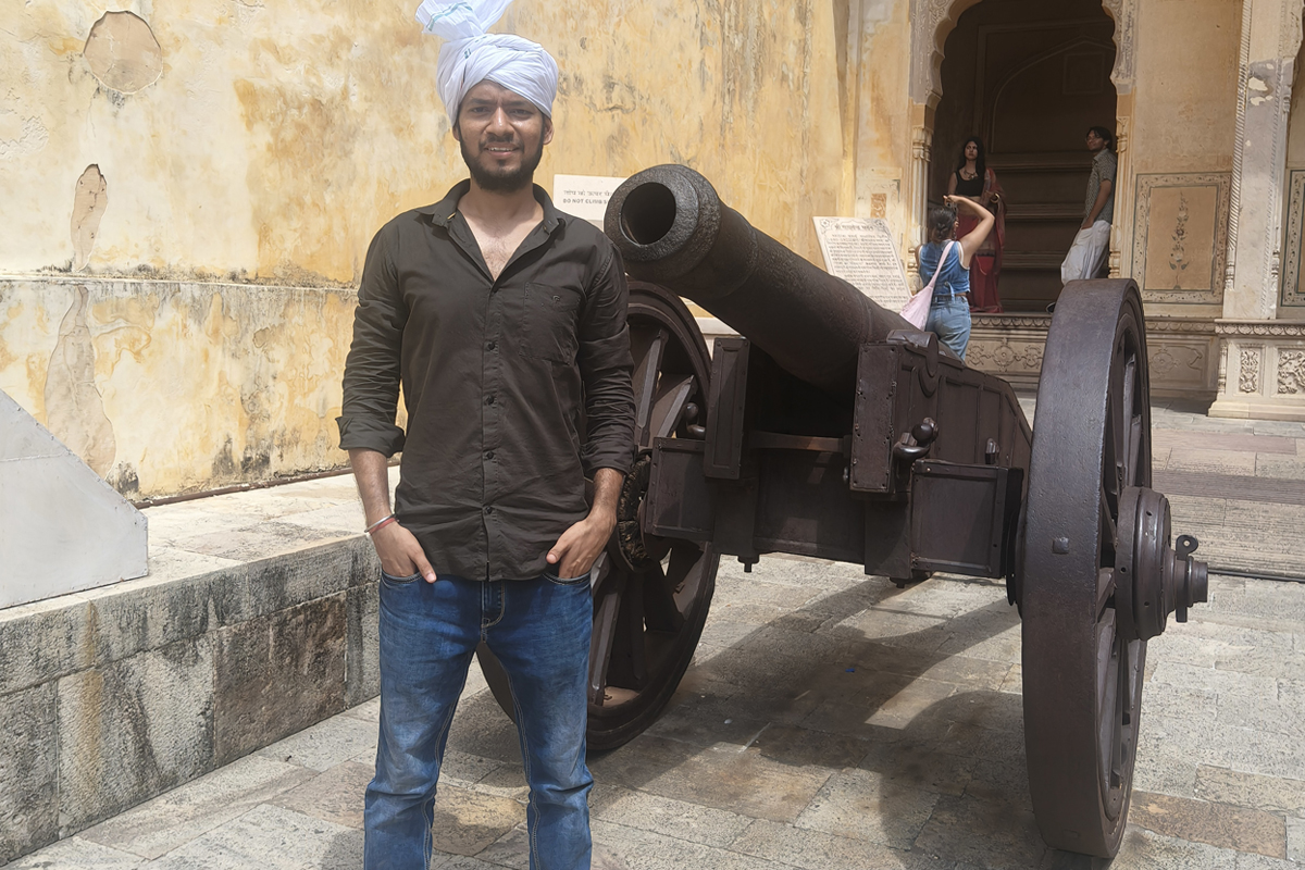 Author wearing a traditional Rajasthani safa turban next to a historic cannon exhibit inside the palace courtyard at Nahargarh Fort in Jaipur taken on 12 July 2026